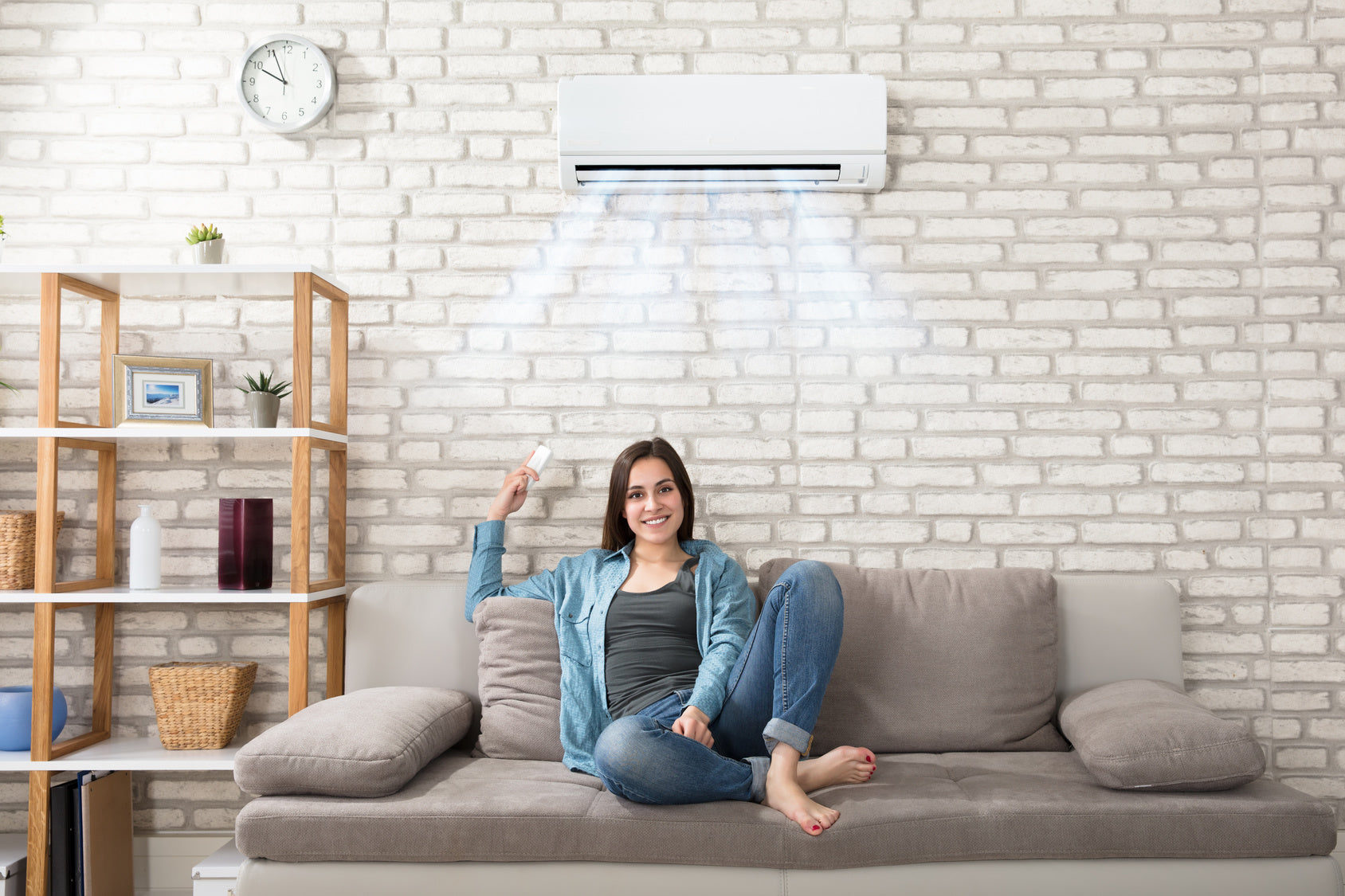 woman sitting on couch with mini split air conditioner overhead